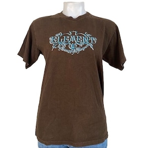 May include: Brown short-sleeved t-shirt with a blue and white graphic of the word "ELEMENT" in a stylised font.