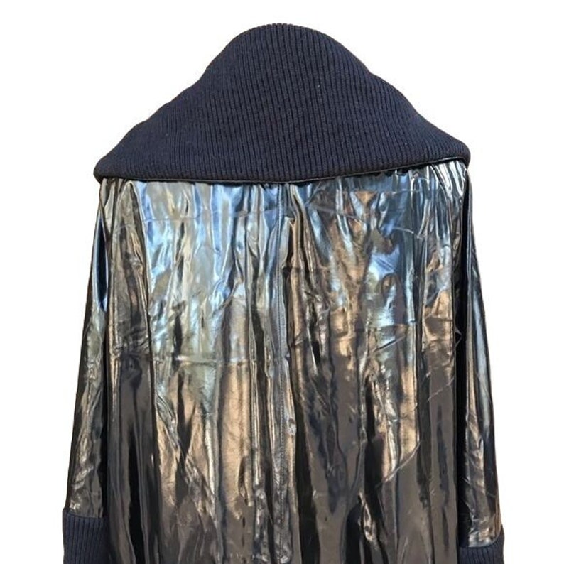 May include: A black, shiny, long-sleeved jacket with a black knit collar.