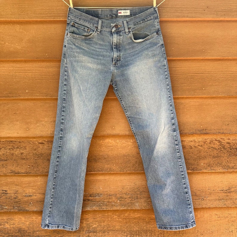 May include: A pair of light blue denim jeans with a straight leg fit. The jeans have a classic five-pocket design and a button fly.