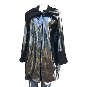 May include: A black, shiny, long-sleeved jacket with a large black collar and black knit cuffs.