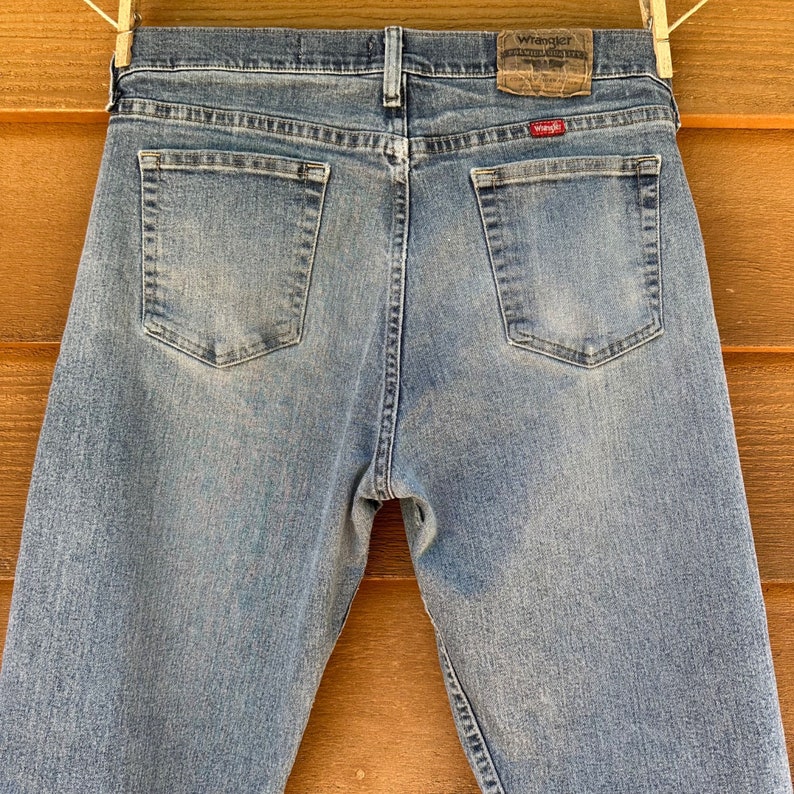 May include: A pair of light blue denim jeans with a Wrangler label on the back pocket. The jeans have a faded look and are made of a soft, comfortable material.