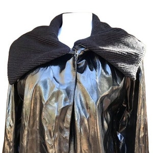 May include: A black, shiny, faux leather jacket with a large, black, knit collar. The jacket has a zipper closure and long sleeves.
