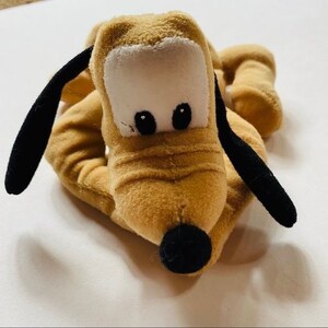 以下が含まれることがあります： 黒い耳と黒い鼻を持つ茶色のぬいぐるみ犬。犬は白い目と顔に白い斑点があります。