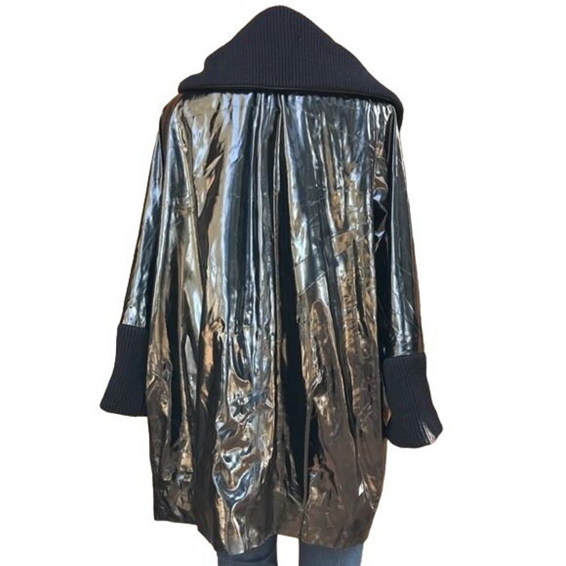 May include: A black, shiny, long-sleeved jacket with a black knit collar and cuffs.