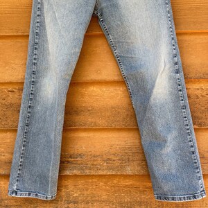 May include: A pair of light blue denim jeans hanging on a wooden surface.