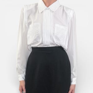 May include: A white ceramic mug with a black handle and the text "But first, coffee" in a handwritten style. The mug is on a white surface. The mug is 4 inches tall.