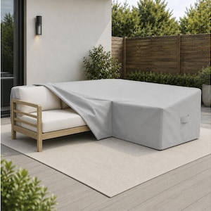 May include: A light gray, rectangular outdoor furniture cover draped over a section of a wooden sofa with cream-colored cushions. The cover features a smooth, solid-colored fabric surface with a small handle visible on the side panel.