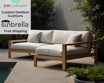 May include: A white sectional sofa with a wooden frame sits on a patio next to a swimming pool. The sofa has a light beige cushion and a dark brown wooden frame. The sofa is made of teak wood. The sofa is next to a swimming pool and a potted plant. The text "ZIPCushions® Custom Outdoor Cushions sunbrella Free Shipping" is visible in the image.