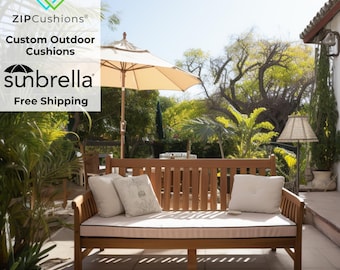 May include: A wooden outdoor sofa with white cushions and a white and brown striped throw pillow. The sofa is on a patio with a white umbrella and green plants.