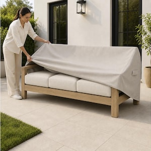 May include: A light beige outdoor sofa cover draped over a three-cushion wooden sofa. The cover is made of a durable fabric and features a side handle for easy adjustment. The sofa has a natural wood frame and off-white cushions underneath.
