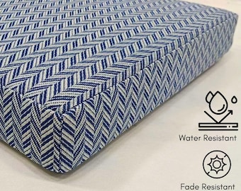May include: A rectangular cushion featuring a blue and white herringbone pattern. The image includes two icons with text: a water droplet icon labeled Water Resistant and a sun icon labeled Fade Resistant, indicating the fabric properties.