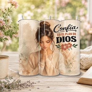 May include: A cylindrical tumbler featuring a beige and cream watercolor background with an illustration of a person with a bun hairstyle praying. The text reads Confia EN EL PLAN DE DIOS above a small floral graphic in shades of red and green.