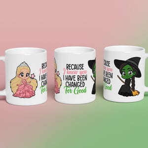 May include: Three white ceramic mugs with cartoon illustrations. One mug features a princess, another has text that reads "BECAUSE I KNEW YOU I HAVE BEEN CHANGED FOR GOOD", and the third depicts a green witch. The mugs are on a pink and green gradient background.
