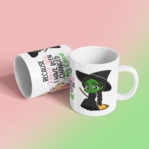 May include: White ceramic mug featuring a cartoon witch with green skin, a black hat, and a black dress, holding a broom. The mug also has the text "Because I knew you I have been changed for Good."