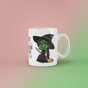 May include: White ceramic mug featuring a cartoon witch with green skin, a black hat, and a black dress. The mug has the text "Because you've been Wicked Good" in black and green. The witch is holding a broom.