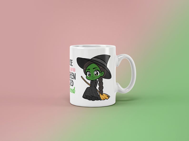May include: White ceramic mug featuring a cartoon witch with green skin, a black hat, and a black dress. The mug has the text "Because you've been Wicked Good" in black and green. The witch is holding a broom.