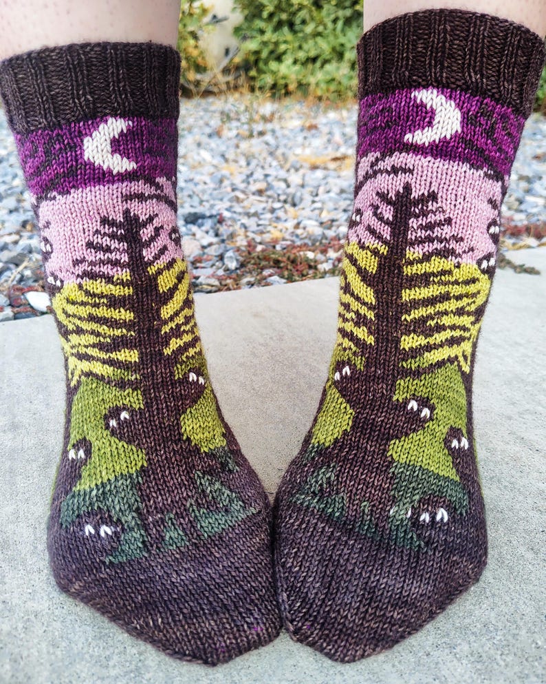 May include: A pair of brown, pink, green, and yellow knitted socks with a moon and tree design.