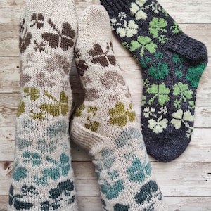 Può includere: Calzini lavorati a maglia con un motivo a trifoglio nei toni del beige, marrone, verde e verde acqua. Un paio è indossato e un altro è esposto separatamente. I calzini sono realizzati con un filato morbido e strutturato.