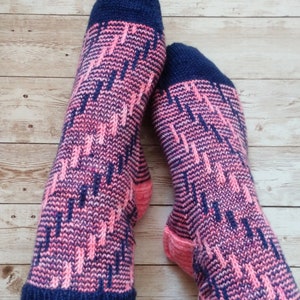 Peut inclure: Une paire de chaussettes tricotées avec un motif géométrique rose et bleu. Les chaussettes sont faites avec un fil doux et ont une coupe confortable.
