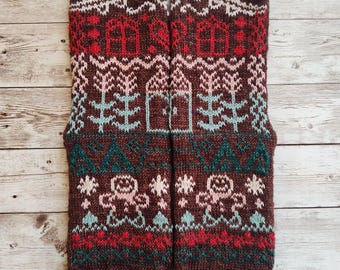 May include: A pair of brown knitted socks with a colorful winter-themed pattern. The pattern includes houses, trees, snowflakes, and gingerbread people.