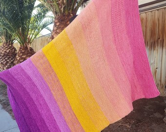 May include: A multi-colored crocheted blanket with stripes of pink, yellow, and purple.