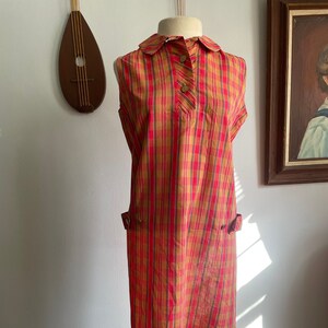 May include: A sleeveless dress with a collared neckline and button closure. The dress is made of a red and gold plaid fabric with thin black stripes.