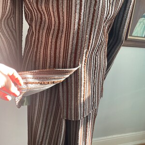 May include: A brown and grey striped trouser suit with a textured fabric. The jacket is open and the trousers are visible.
