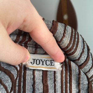 May include: A close-up of a brown and grey striped shirt with a white label that reads "JOYCE".