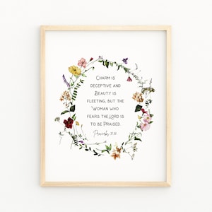 Op de afbeelding: Een bloemenkrans op een witte achtergrond met de tekst "Charme is bedrieglijk en schoonheid is vergankelijk, maar de vrouw die de Heer vreest, zal geprezen worden. Spreuken 31:30"