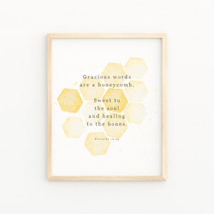 May include: A framed print featuring the quote "Gracious words are a honeycomb, sweet to the soul and healing to the bones." The artwork has a light wood frame and a watercolor honeycomb design in shades of yellow.