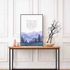 Puede incluir: Una impresi&oacute;n de acuarela con una cita de Proverbios 22:6, "Instruye al ni&ntilde;o en el camino que debe andar, y aun cuando fuere viejo no se apartar&aacute; de &eacute;l." La impresi&oacute;n presenta un paisaje de acuarela de monta&ntilde;as y &aacute;rboles en tonos azules y verdes.