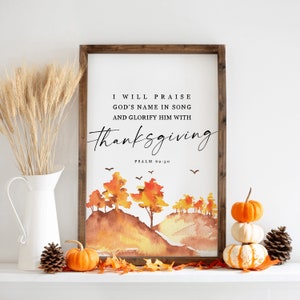 May include: A framed watercolor print with a fall landscape and the text "I will praise God's name in song and glorify him with thanksgiving. Psalm 69:30."