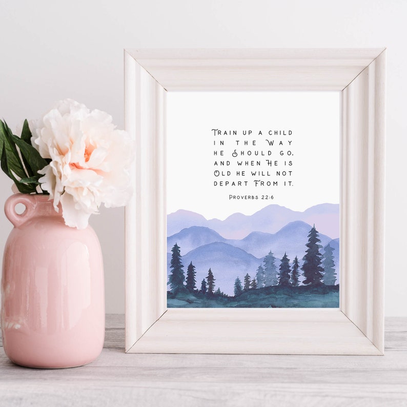 Puede incluir: Una impresi&oacute;n enmarcada con una ilustraci&oacute;n de acuarela de una cordillera con un cielo azul y morado. La impresi&oacute;n presenta el vers&iacute;culo b&iacute;blico "Instruye al ni&ntilde;o en el camino en que debe andar, y aun cuando fuere viejo no se apartar&aacute; de &eacute;l." Proverbios 22:6