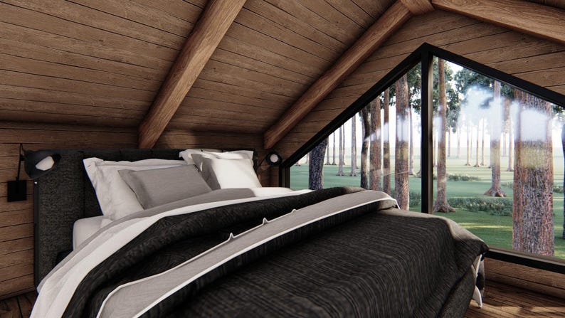 May include: A cozy bedroom with a bed covered in a dark gray comforter and white pillows. The room has wooden walls and ceiling, and a large triangular window offering a view of a forest.