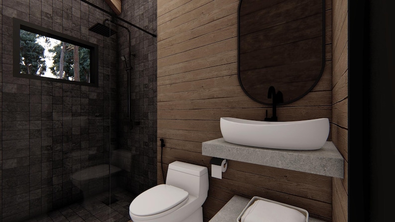 May include: Modern bathroom interior with a dark tiled shower area and a wooden wall. Features a white sink on a concrete shelf, a toilet, and a large oval mirror. The shower has a black shower head and a window with a view of trees.