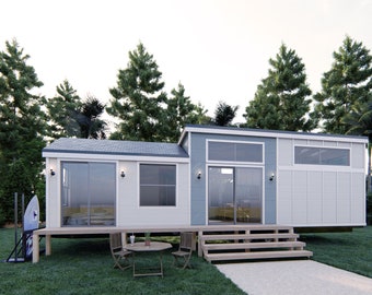 May include: A small, modern, white and blue house with a wooden deck and steps. The house has large windows and a flat roof. The house is surrounded by trees and grass.