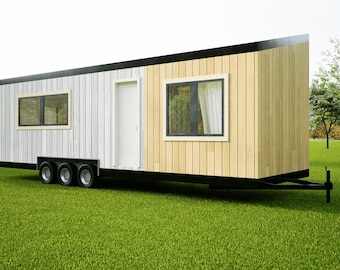 May include: A white and wood-paneled tiny home on wheels with a black trim. The home has a door and two windows. The home is parked on a grassy lawn.