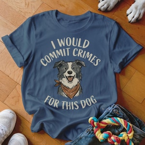May include: A navy blue t-shirt with the text "I WOULD COMMIT CRIMES FOR THIS DOG" above a smiling dog illustration wearing a brown bandana. The dog is black and white. The shirt is folded.