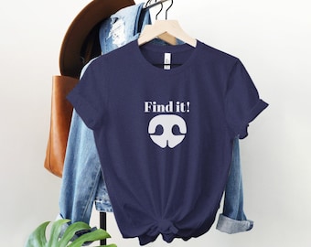 May include: A navy blue t-shirt with a white graphic of a nose and the text "Find it!" printed on the front.