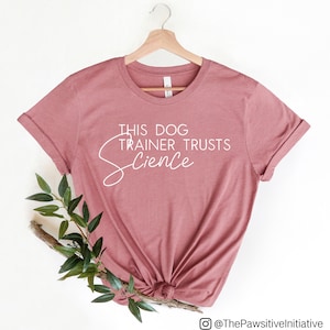 Pode incluir: Uma camiseta rosa pó com o texto "This Dog Trainer Trusts Science" em escrita branca.
