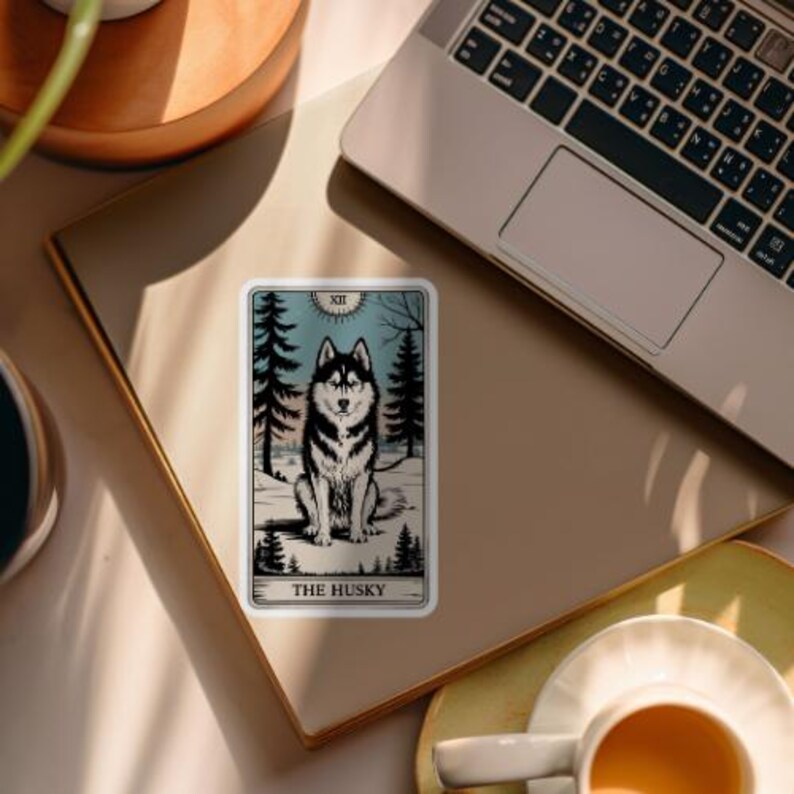 May include: A sticker featuring a tarot card illustration of a husky dog in a snowy forest setting. The card is titled "The Husky" and has the Roman numeral XII at the top.