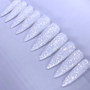 May include: A set of ten white glitter stiletto false nails. The nails are long and pointed, with a sparkly finish.