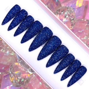 K&ouml;nnte beinhalten: Set mit zehn blauen Glitzer-Press-on-N&auml;geln in Stiletto-Form.