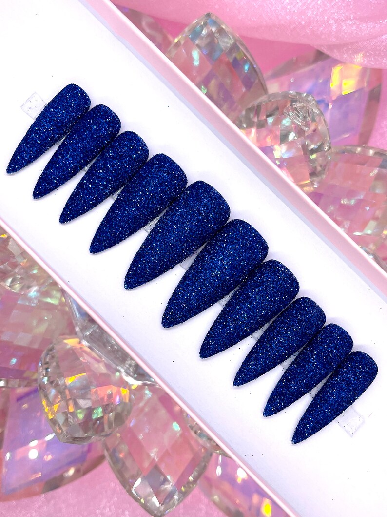 K&ouml;nnte beinhalten: Set mit zehn blauen Glitzer-Press-on-N&auml;geln in Stiletto-Form.
