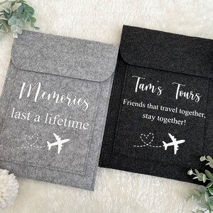 May include: Two gray felt pouches with white text and airplane designs. The pouch on the left says "Memories last a lifetime". The pouch on the right says "Tam's Tours Friends that travel together, stay together!"