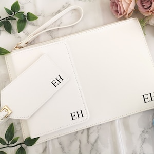 May include: White leather clutch with a matching luggage tag. Both items have the initials "EH" embossed in black.