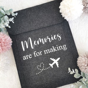 May include: A gray felt pouch with the text "Memories are for making" and a white airplane with a dotted line leading to a heart.