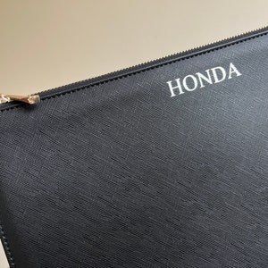 May include: Black zippered pouch with the word "HONDA" printed in white on the front.