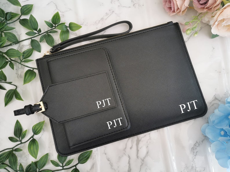 May include: Black leather travel pouch with two zippered pockets and a luggage tag. The pouch and tag are personalized with the initials "PJT".