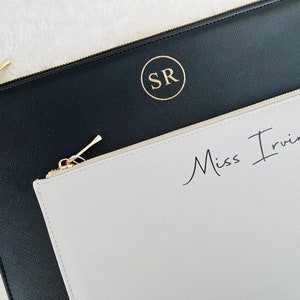 May include: Two zippered pouches, one black with gold initials "SR" and one light gray with the text "Miss Irving" in black.